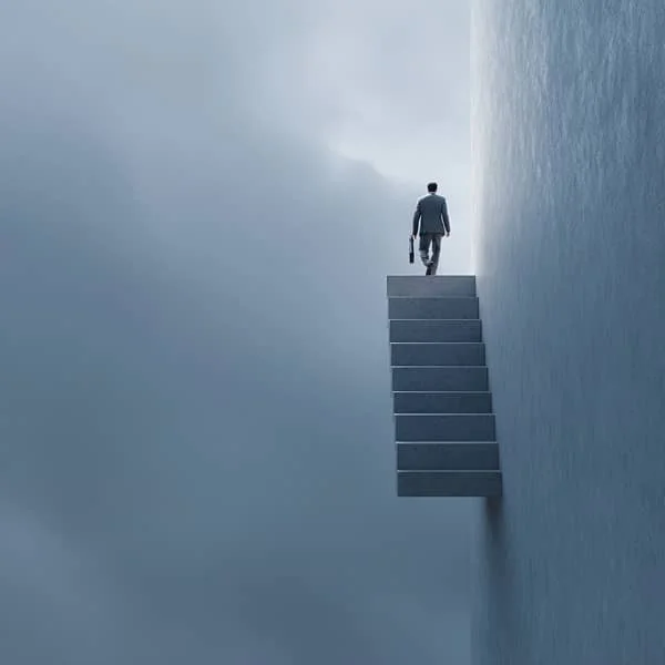 Homme d’affaires montant un escalier suspendu dans les nuages, symbolisant la progression de carrière ou la réussite professionnelle.
