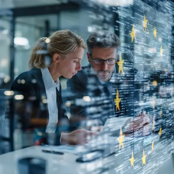 Deux professionnels RH examinent des documents numériques dans un bureau moderne, avec en surimpression des étoiles du drapeau européen et des données, illustrant l’application de l’AI Act dans les ressources humaines.