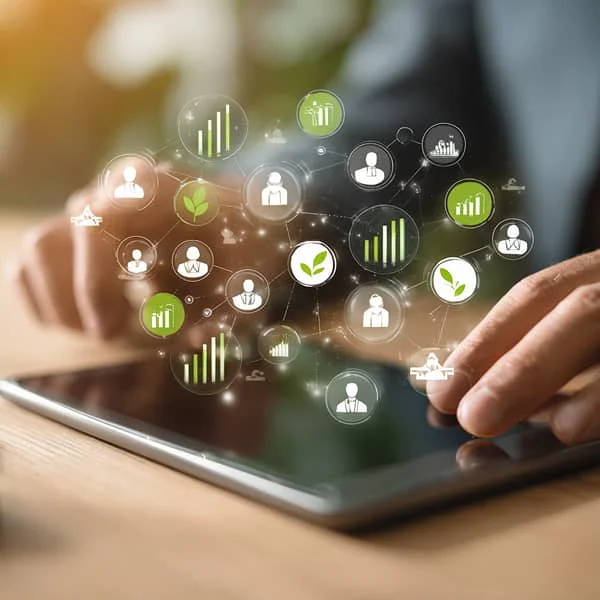 Main utilisant une tablette affichant des icônes de croissance et de feuilles vertes, symbolisant les green skills et le développement durable en entreprise.