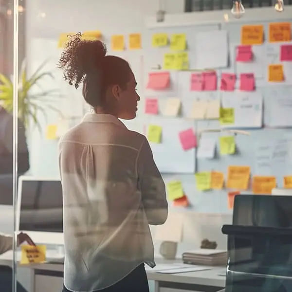 Responsable RH observant un mur de post-its lors d’un atelier de conduite du changement en entreprise