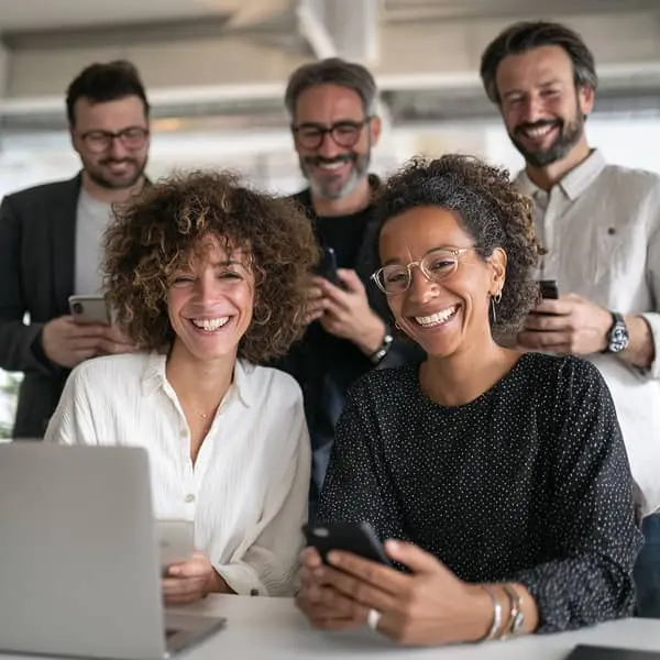 Equipo de empleados compartiendo contenidos profesionales desde sus móviles y portátil, concepto de Employee Advocacy y embajadores de marca.