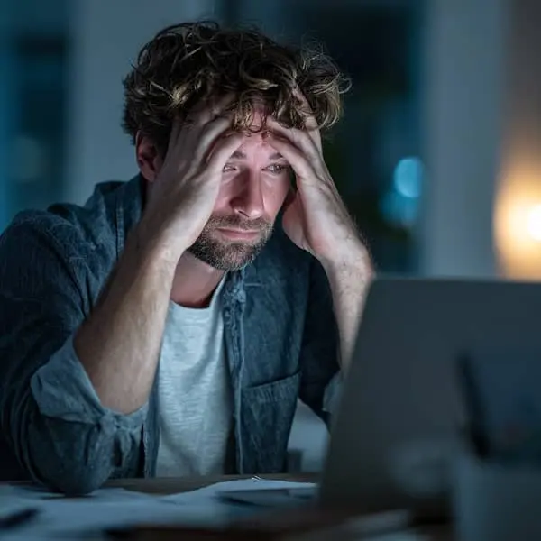 employé avec la tête entre ses mains, accoudé à son bureau, dans un état d'épuisement professionnel