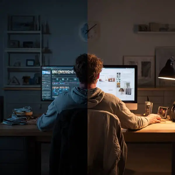 Un salarié travaille sur deux ordinateurs dans la même pièce, l’image divisée en deux moitiés contrastant le jour et la nuit, symbolisant le cumul d’activités professionnelles en dehors du temps de travail.