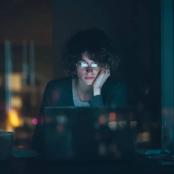 Personne fatiguée devant son ordinateur la nuit, symbole du doomjobbing et de la recherche d’emploi en boucle.