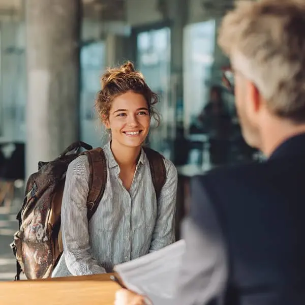 Jeune étudiante stagiaire avec sac à dos en entretien avec un recruteur, illustrant la rémunération des stagiaires en 2026