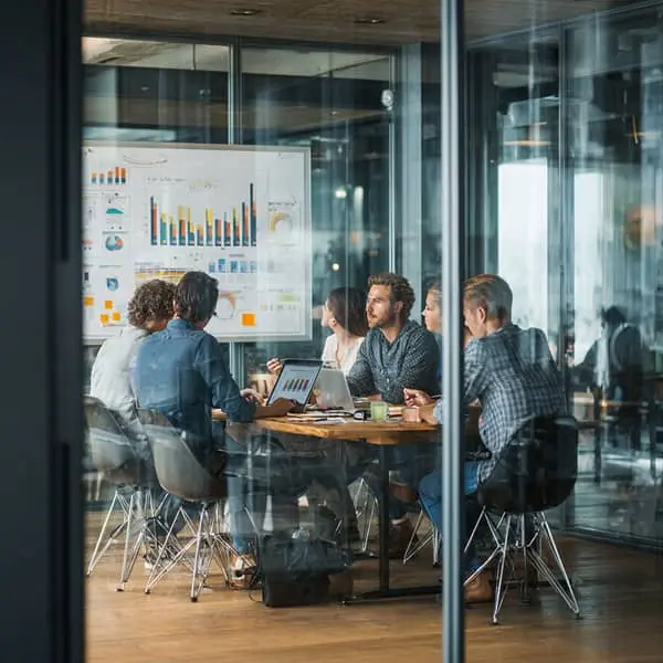 equipo en reunión estratégica analizando OKR y KPI en sala de reuniones moderna con gráficos y objetivos en pantalla